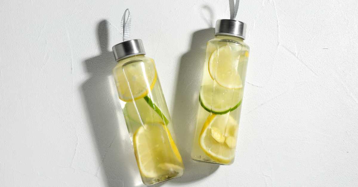 Wasserflasche und aromatisiertes Wasser mit Zitrone und Gurke als Alltagshilfe für mehr Trinken
