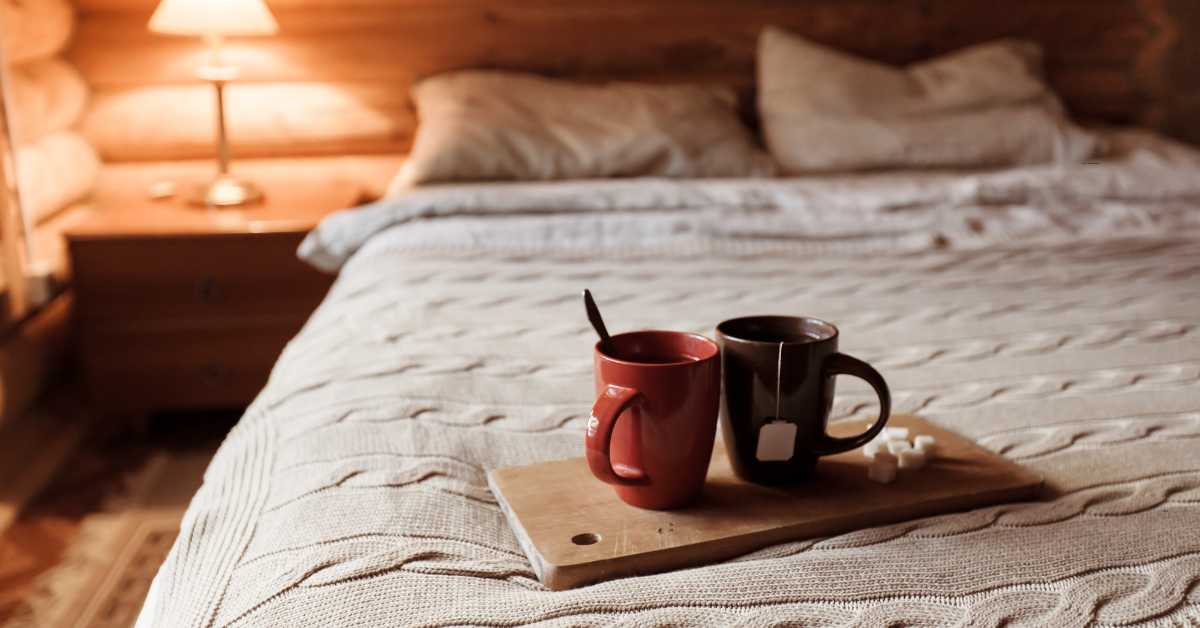 Tasse Kräutertee auf Nachttisch als Abendritual zum Einschlafen